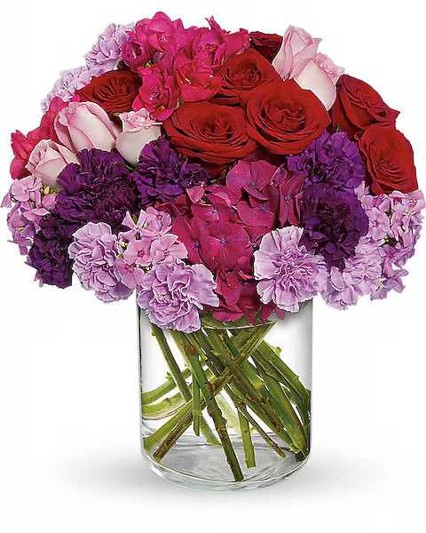 Bouquet of red, pink, and purple flowers in a clear vase 