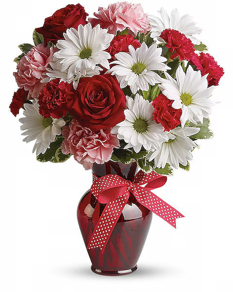 Bouquet of red, pink, and white flowers in a red vase with a red bow 