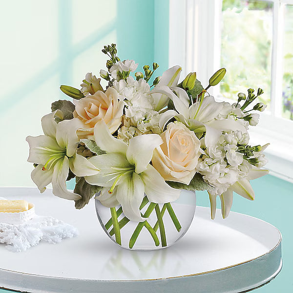 White lilies and peach roses in glass vase for modern home interior