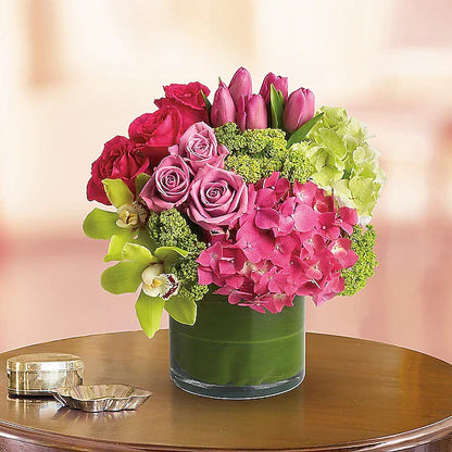 Bright pink and green flowers arranged in a glass vase.