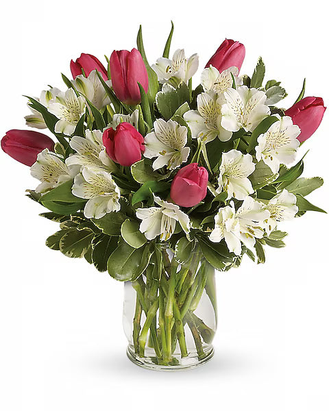 Bouquet of pink tulips and white alstroemeria in a clear vase on a white background