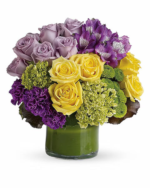 Cheerful mixed flower display in glass vase against white background